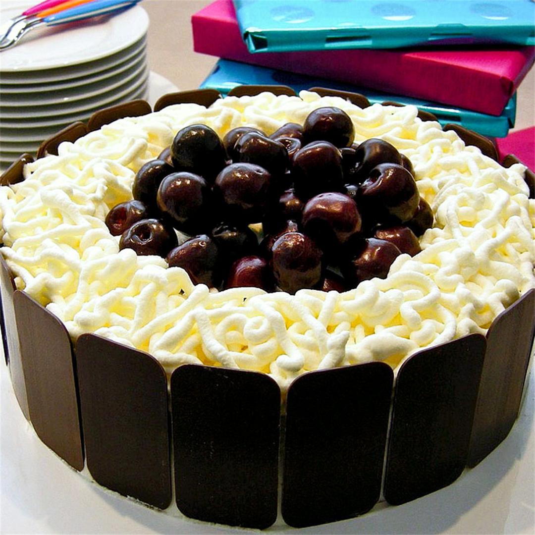 Light chocolate cake with cherries, whipped cream and kirsch